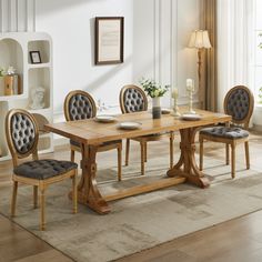 a dining room table with four chairs and a rug on the floor in front of it