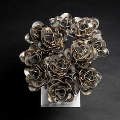 a bunch of metal flowers sitting on top of a silver stand with one flower in it's center