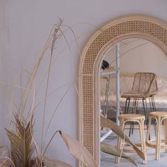 a mirror sitting on the side of a wall next to some chairs and table top