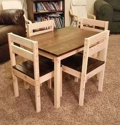 a wooden table and chairs sitting in front of a book shelf with books on it