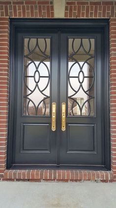 a black double door with gold handles and glass on the front entrance to a brick building