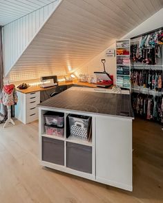 a room with some shelves and clothes on the wall next to a desk in front of a window