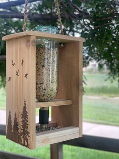 a wooden bird feeder hanging from a tree