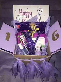 a purple gift box filled with lots of goodies and confetti for someone's birthday