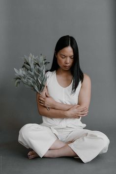 a woman sitting on the floor holding a plant