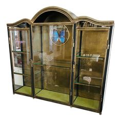 an antique china cabinet with glass doors and gold trimmings, in the shape of a butterfly