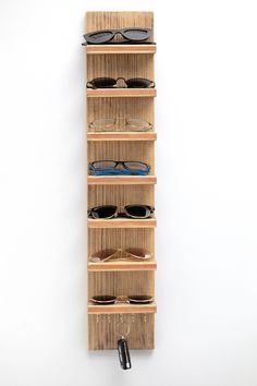 a wooden shelf with glasses hanging from it's sides and two pairs of eyeglasses on top