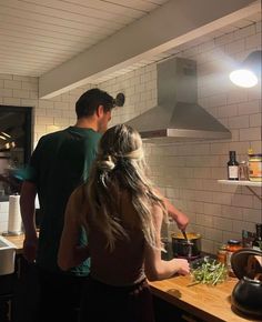 a man and woman are cooking in the kitchen