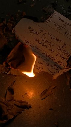 a candle is lit in front of a piece of paper with writing on it