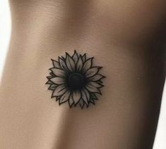 a black and white sunflower tattoo on the side of a woman's stomach