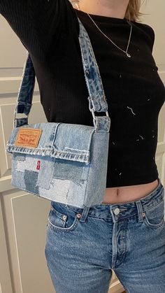 a woman is holding her cell phone in one hand and an old jean purse on the other