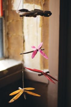 three paper flowers hanging from strings in front of a window