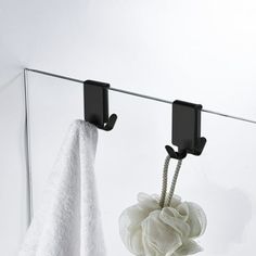 two towels hanging from hooks on a towel rack next to a white towel and black soap dispenser