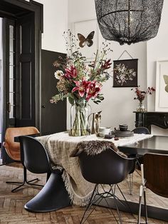 a dining room table with chairs and a vase filled with flowers on top of it