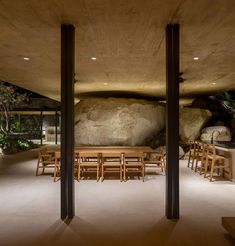 an outdoor dining area with wooden tables and chairs, surrounded by large rocks in the background