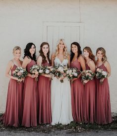 a group of women standing next to each other wearing dresses and holding bouquets in their hands