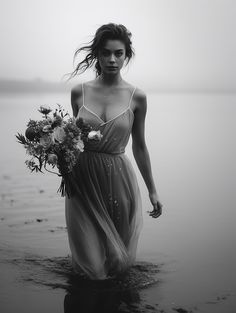 a woman standing in the water holding flowers