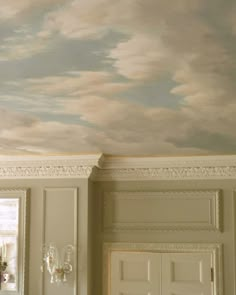 an empty room with white walls and clouds painted on the ceiling above it is a chandelier