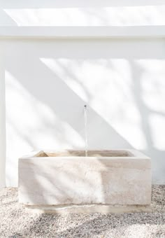 a white building with a water fountain in front of it and shadows on the wall