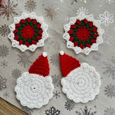 three crocheted christmas ornaments on a table with snowflakes in the background