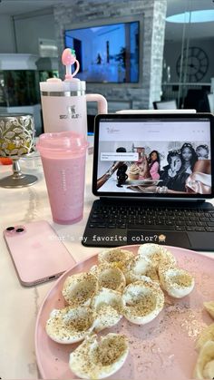 an open laptop computer sitting on top of a pink plate filled with hard boiled eggs