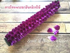 purple flowers are arranged in the shape of hearts on a wooden surface with thai writing