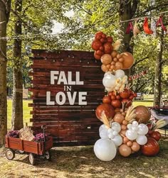 a sign that says fall in love with balloons attached to it and an assortment of other decorations