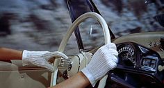 black and white photograph of a woman driving a car with her hand on the steering wheel