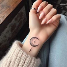 a woman's wrist with a small crescent tattoo on the left side of her arm