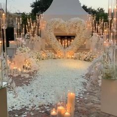 a wedding ceremony with candles and flowers on the ground in front of a heart - shaped fireplace