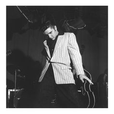 black and white photograph of a man in a suit holding a violin while standing on stage