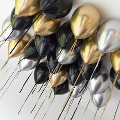 a bunch of balloons that are hanging on the side of a wall with gold and black decorations