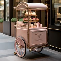 a pink and gold cart with cupcakes on it