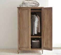 a wooden cabinet with clothes hanging on it's sides and a basket next to it