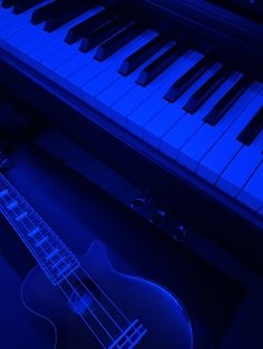 an electric guitar sitting in front of a piano with blue lights on it's sides