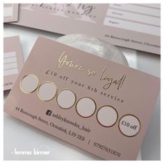 some business cards sitting on top of a white table with gold foil lettering and circles