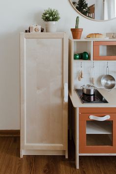 a small wooden kitchen with an oven, sink and mirror on the wall above it