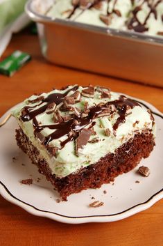 a piece of cake sitting on top of a white plate next to a pan filled with frosting