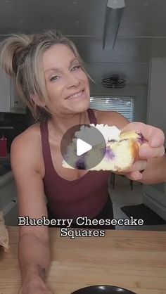 a woman holding up a piece of food in her right hand and smiling at the camera