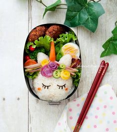 a bento box filled with rice, vegetables and meats on top of a table