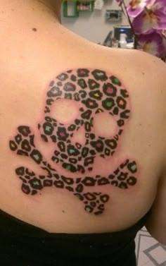 a skull and crossbone tattoo on the back of a woman's shoulder