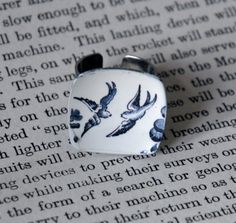 a ring with two birds on it sitting on top of an open page of a book