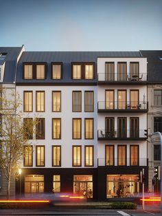 an apartment building with many windows on the front and side of it at night time