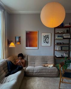 a person sitting on a couch in a living room next to a table and lamp