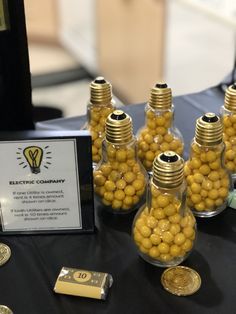 there are many small glass bottles with yellow balls in them on the table next to some gold coins