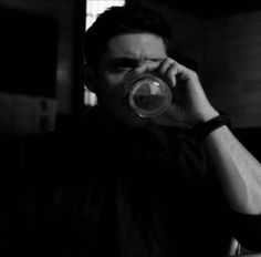 a man drinking from a glass while sitting at a table with his hand on his face