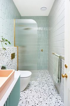 a bathroom with green and white tiles on the walls, floor, and shower stall