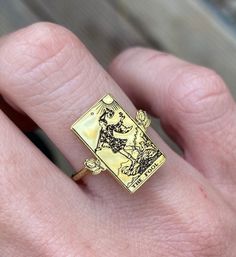 a person's hand holding a gold ring with an image of a man on it