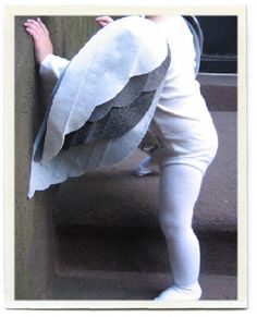 a little boy dressed as an owl climbing up the stairs with his hands on the wall