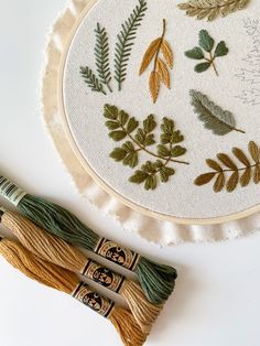 three different types of embroiderys on a white surface next to some thread and needles